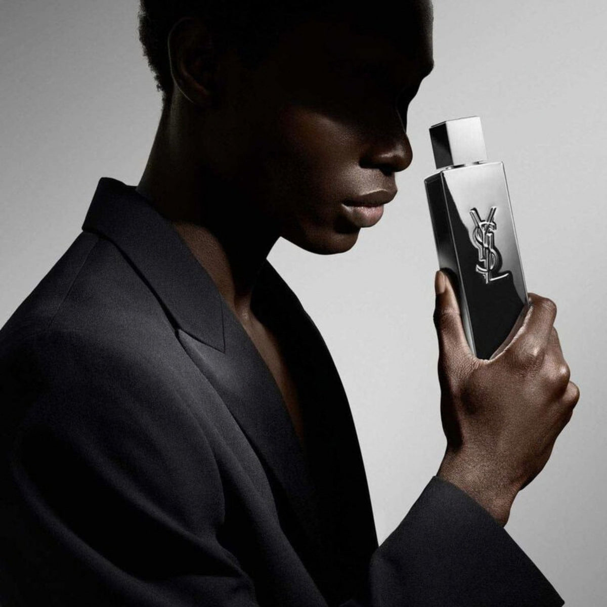 Refect Beauty model holding the metallic mirror Yves Saint Laurent Myslf L'Absolu fragrance bottle in a studio shot