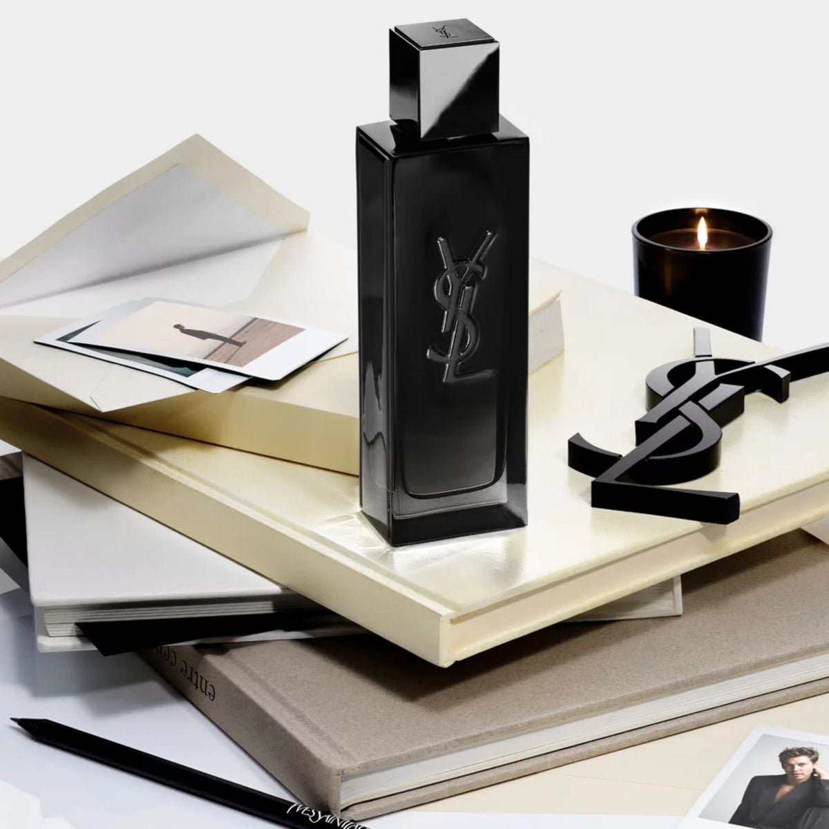 Refect Beauty Yves Saint Laurent MYSLF Eau de Parfum bottle on a stack of books with a candle and YSL logo