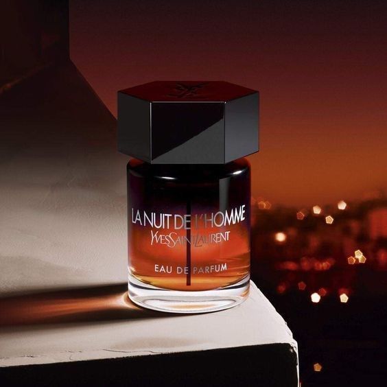 Refect Beauty Yves Saint Laurent La Nuit De L'Homme Eau de Parfum bottle with a dark amber gradient against a sunset