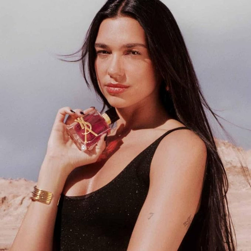 Refect Beauty model holding a bottle of Yves Saint Laurent Libre Berry Crush perfume in a desert landscape