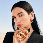 Refect Beauty model holding Yves Saint Laurent Libre Flowers & Flames perfume bottle with gold logo in desert setting