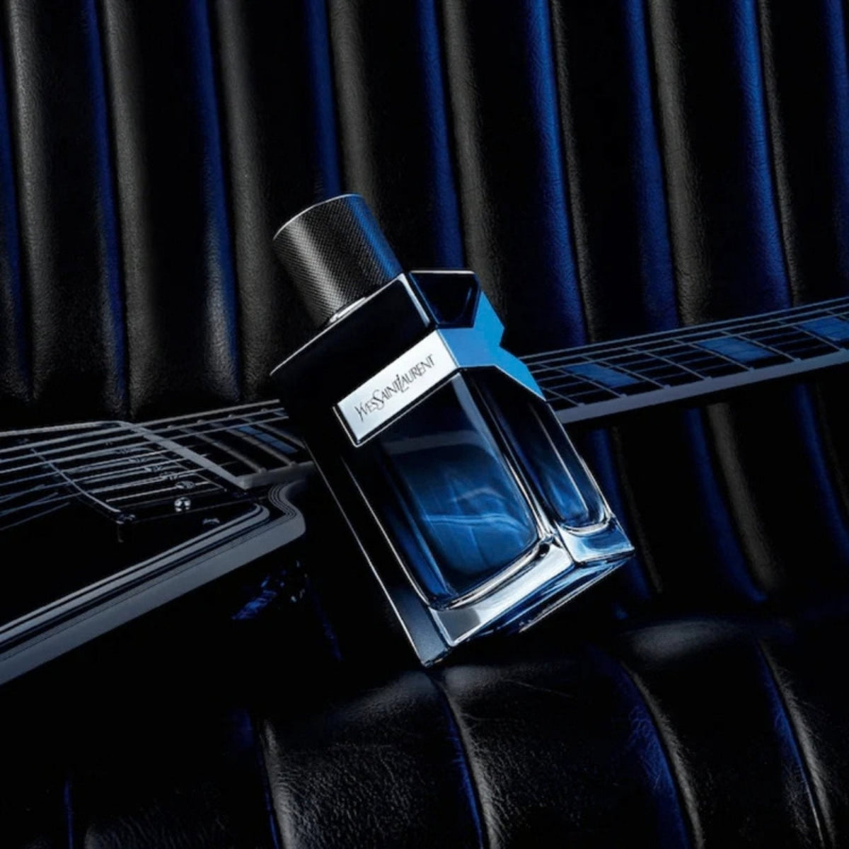 Refect Beauty Yves Saint Laurent Y Eau de Parfum bottle resting on a black electric guitar against a leather background